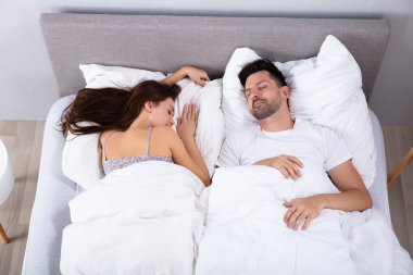 Yüksek açı görünüm arasında genç çift Sleeping üzerinde yatak
