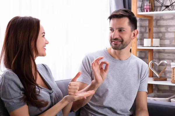 Sonriente Pareja Joven Sentada Sofá Comunicándose Con Lenguajes Señas — Foto de Stock