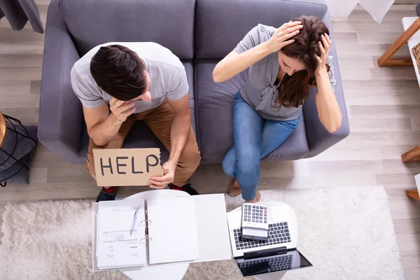 Jonge Paar Zittend Sofa Holding Help Sign Tijdens Het Berekenen — Stockfoto