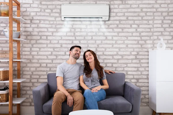 Glückliches Junges Paar Sitzt Unter Klimaanlage Auf Couch Hause — Stockfoto
