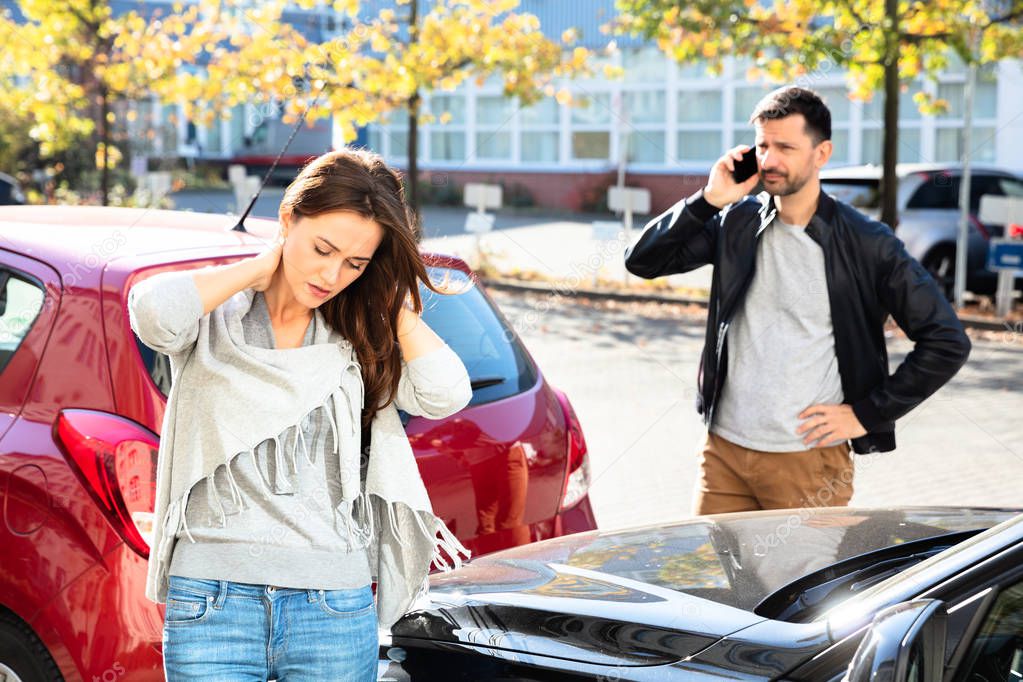 Man Calling For Assistance In Front Of Sad Woman Looking Damaged Car On Road