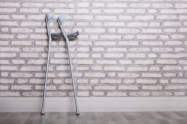 Tuğla duvara yaslanan bir çift koltuk değneği