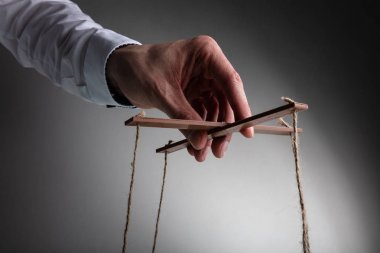 Bir Işadamı el Gri arka plan karşı dize Ile Marionette manipüle