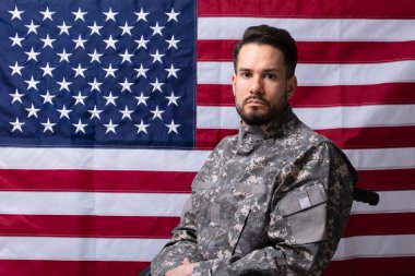 Bir Amerikan bayrağı önünde tekerlekli sandalyede oturan Veteran yan görünümü