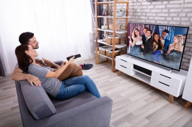 Genç Couple oturma üzerinde koltuk Izlerken televizyon evde