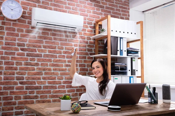 Close Empresária Ajustando Temperatura Condicionado Com Controle Remoto Local Trabalho — Fotografia de Stock