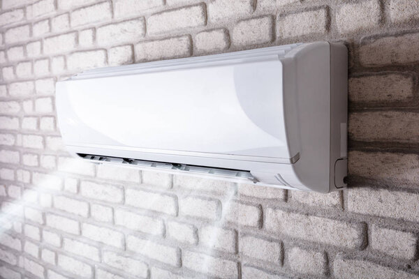White Air Conditioner Blowing Cold Air On Brick Wall In Living Room