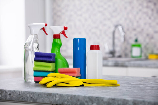 Close-up Of Cleaning Supplies And Yellow Handgloves On The Kitchen Countertop