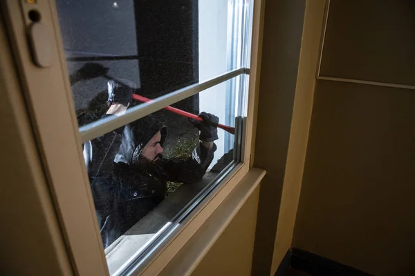 泥棒は夜にクラウバーで窓を破るしようとします — ストック写真