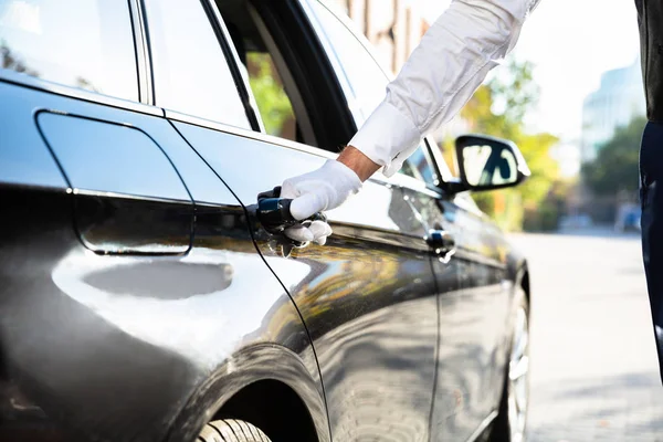 Diener Öffnet Schwarze Autotür Auf Der Straße — Stockfoto