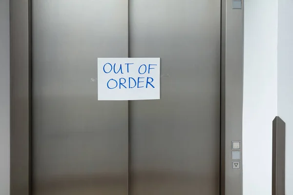クローズドエレベーターのドアに白い紙で注文メッセージのテキストを書きます — ストック写真