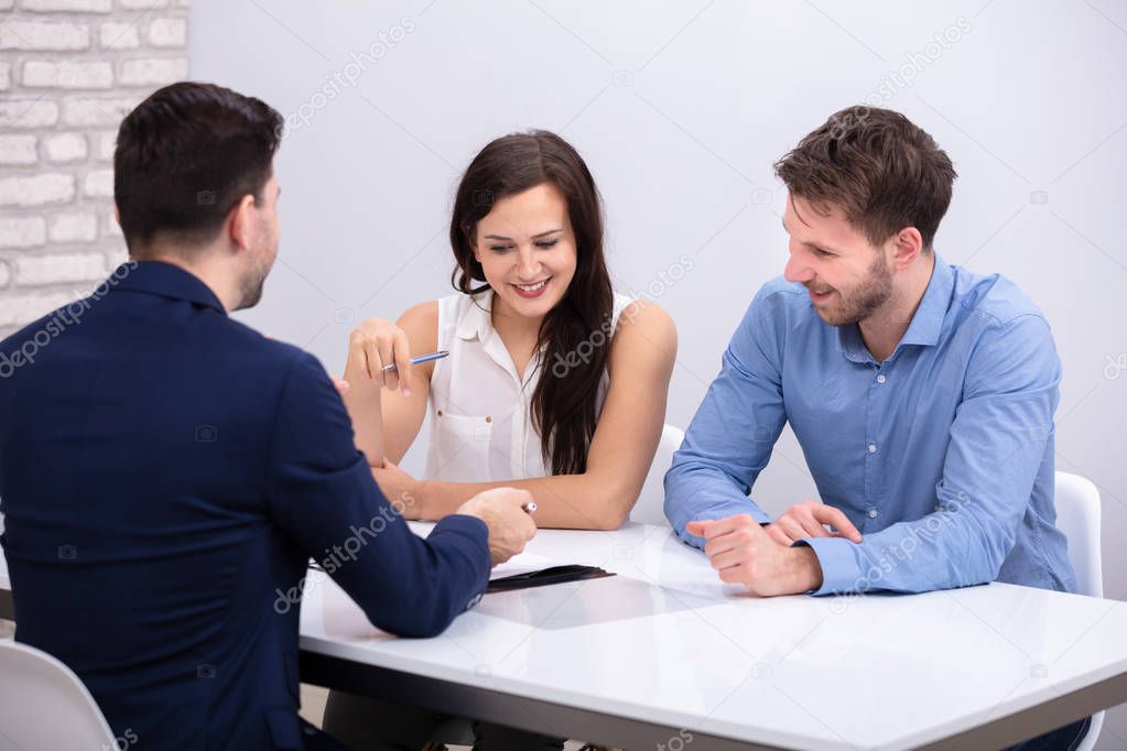 Rear View Of Advisor Sitting With Smiling Young Couple