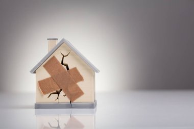 Masasında çapraz yara bandı olan kırık ev modeli.