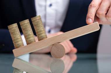 İşadamı Ahşap Tahterevalli Üzerinde Parmak ile Yığılmış Madeni Paralar Dengeleme Reflektif Masa Üzerinde