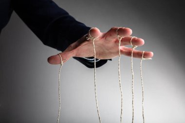 Kişinin Eli Kuklayı Gri Arkaplana Karşı Kontrol Ediyor