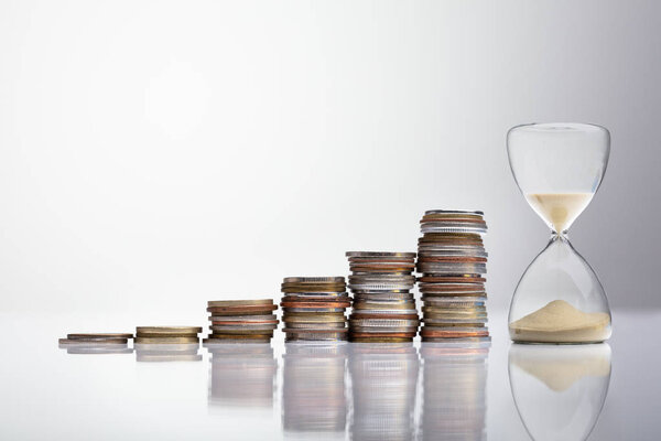 Крупный план часов рядом со стопкой монет над столом
