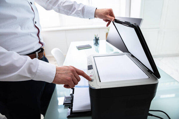 Close-up Of Businessman Pressing Printer's Button In Office