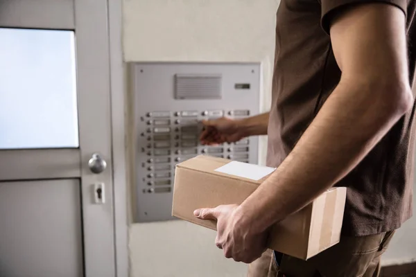 Bagian Tengah Dari Man Holding Cardboard Box Ringing Intercom — Stok Foto