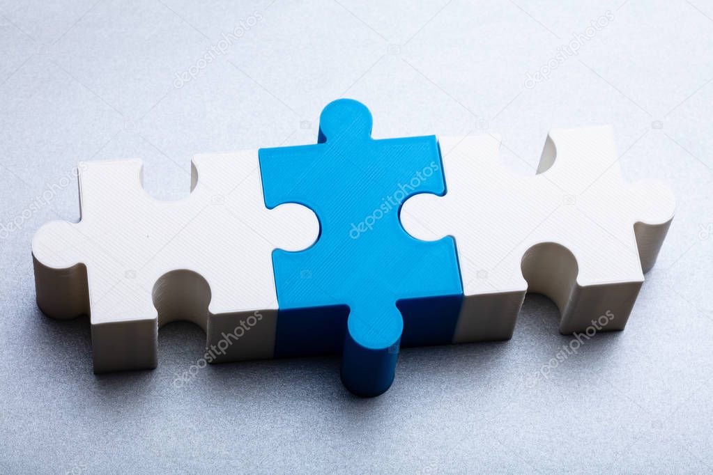 Close-up Of White And Blue Jigsaw Puzzle Block On White Textured Background