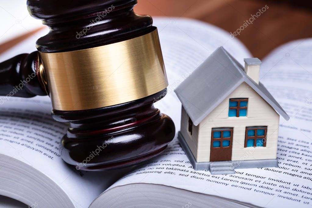 Close-up Of Miniature House And Gavel On Open Book