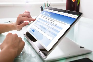 Yakın çekim A Businessperson el dolum online anket formu üzerinde dijital dizüstü Office