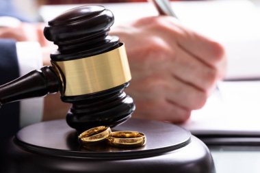 Tahta ses bloğunda, mahkeme salonundaki çekiçle düğün yüzüklerinin yakın çekimi.