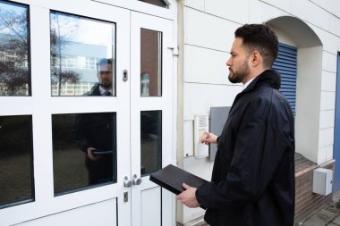 Evin girişinde duran bir adam kapı ziline basıyor.