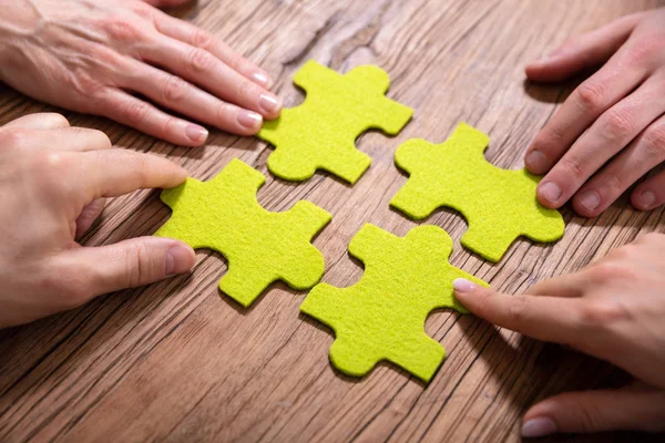 People Hand Touching Green Puzzle Drewnianym Biurku — Zdjęcie stockowe