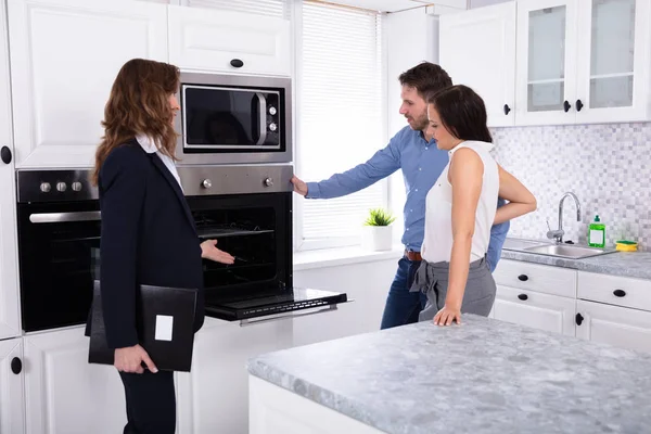 Real Estate Agent Showing Microwave Oven House Young Couple — Stock Photo, Image