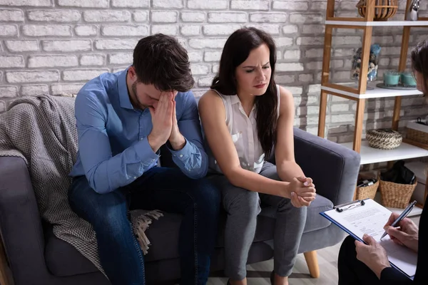 Psychologist Talking With Depressed Young Couple About Mental Condition In Home
