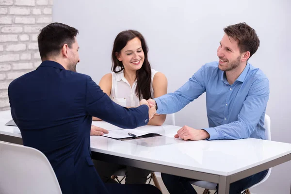 Close Conselheiro Handshaking Com Casal Jovem Sorridente Após Acordo — Fotografia de Stock