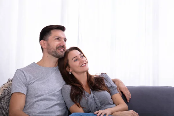Lächelndes Kontemplatives Paar Das Hause Auf Der Couch Sitzt — Stockfoto