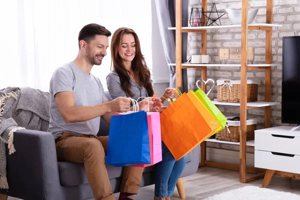Happy Couple Sitting Sofa Looking Shopping Bag Home — Stock Photo, Image