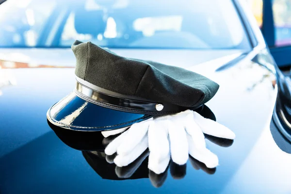 Black Chauffeur's Cap And Pair Of White Hand Gloves On Car Bonnet