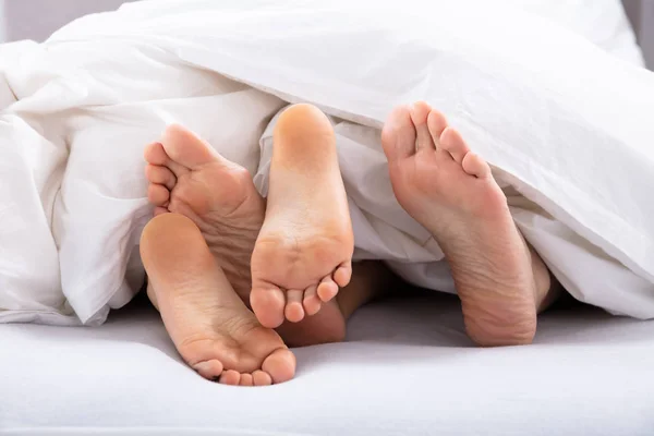 Çiftin Beyaz Battaniyenin Altındaki Çıplak Ayakların Yakın Çekimi — Stok fotoğraf