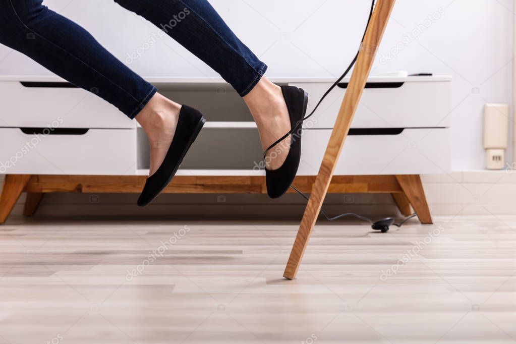 Close-up Of A Woman Legs Stumbling With An Electrical Cord At Home