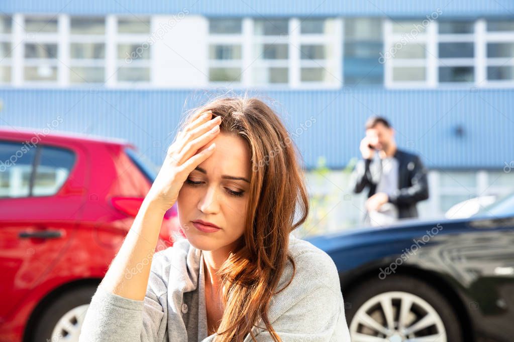Young Depressed Female Driver After Traffic Accident Sitting On Road