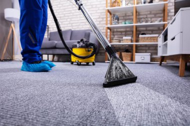 Evdeki elektrikli süpürgeyi kullanarak oturma odasındaki insan temizleme halısı.