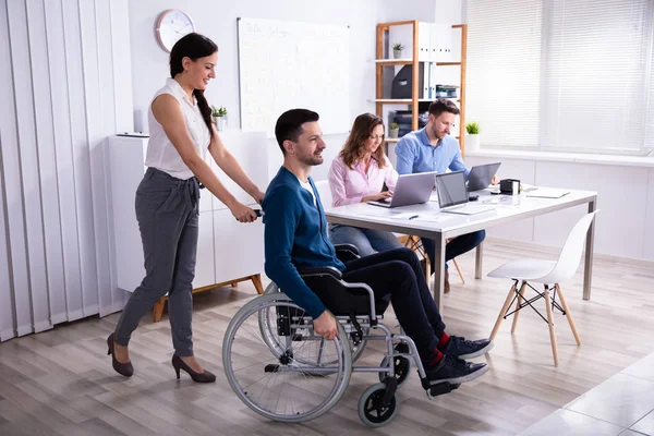 Joven Empresaria Sonriente Ayudando Colega Discapacitado Silla Ruedas — Foto de Stock