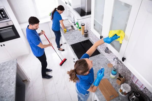 自宅で制服洗浄キッチンで若い管理人のグループ — ストック写真