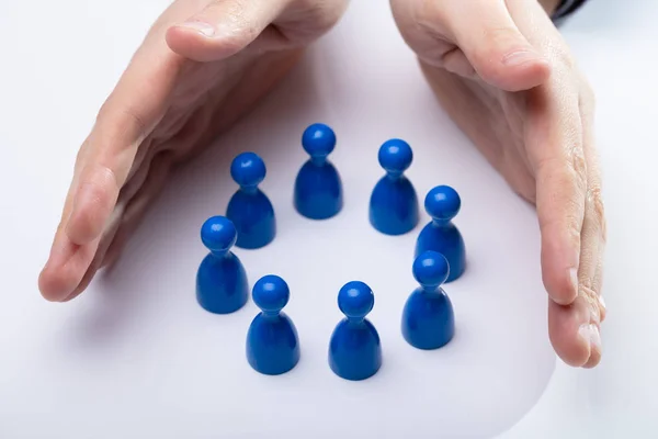 Close Person Hand Protecting Blue Pawns Forming Circle — Stock Photo, Image