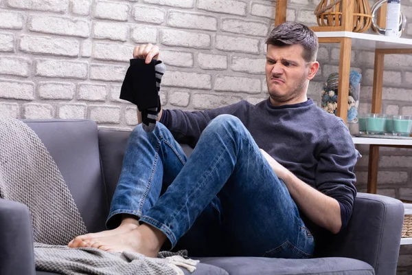 Koltukta Oturan Genç Adam Kirli Çorap Tutuyor — Stok fotoğraf