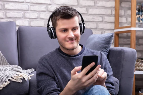 Happy Man Leaning Sofa Podczas Słuchania Muzyki Słuchawkami Bezprzewodowymi — Zdjęcie stockowe