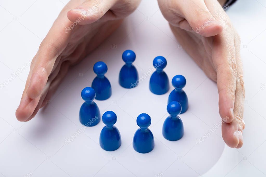 Close-up Of A Person's Hand Protecting Blue Pawns Forming Circle