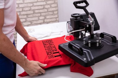 Man printing on t shirt in workshop clipart