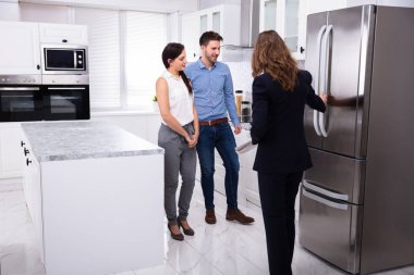 Profesyonel Emlakçı Genç Bir Çift evde buzdolabı gösteren