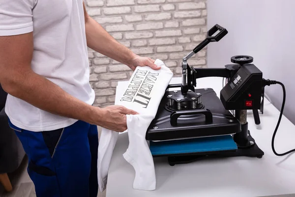 Man printing on t shirt in workshop