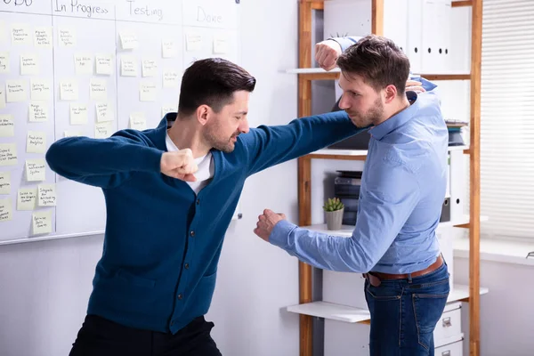 Close-up Of Businessmen Getting Into A Fight Woman Trying To Separate Them In Office