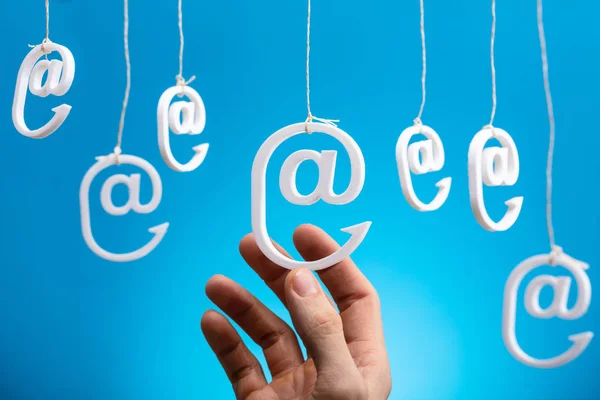 Human Hand Holding Hanging Email Icons Blue Background — стоковое фото