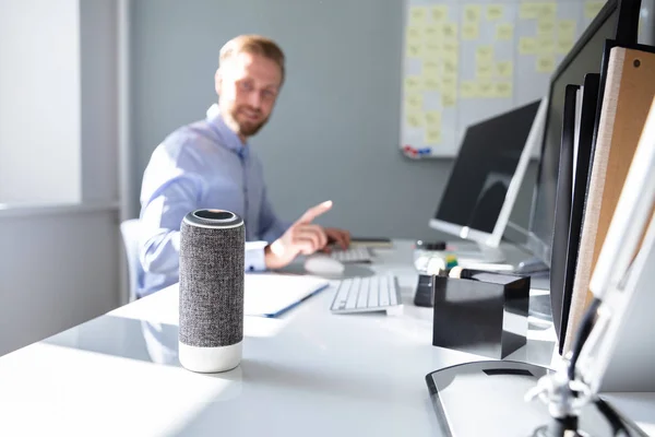 Close-up Of Voice Assistant In Front Of Businessman Working At Desk